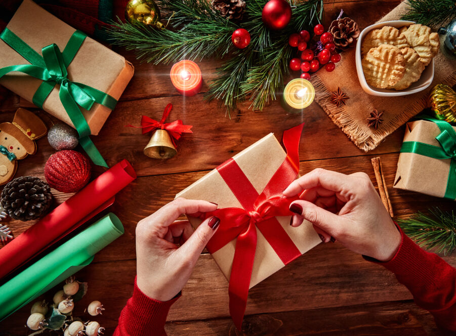 Top view of woman hands with Christmas present on rustic wooden table