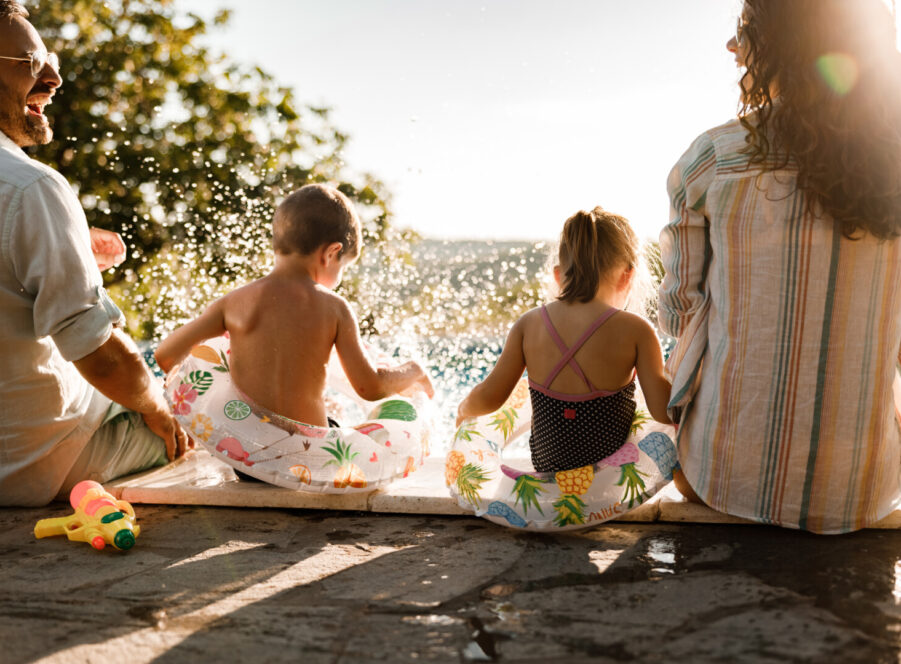 Happy family having fun by the pool in summer day.