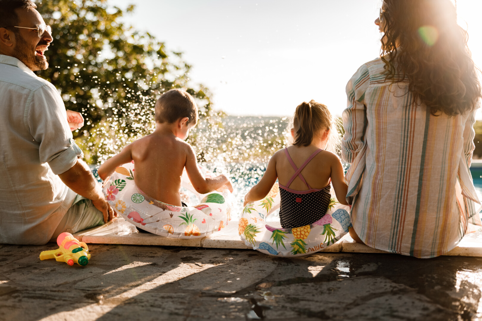 Happy family having fun by the pool in summer day.